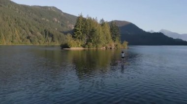 Huzurlu bir gölde kürek çeken maceraperest bir kadın. Güneşli Günbatımı. Hicks Lake, Sasquatch İl Parkı Harrison Hot Springs, British Columbia, Kanada yakınlarında. Yavaş Hareket
