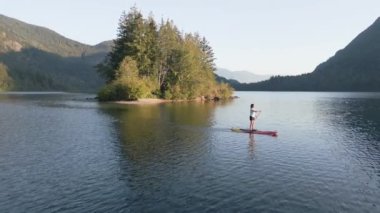 Huzurlu bir gölde kürek çeken maceraperest bir kadın. Güneşli Günbatımı. Hicks Lake, Sasquatch İl Parkı Harrison Hot Springs, British Columbia, Kanada yakınlarında. Yavaş Hareket