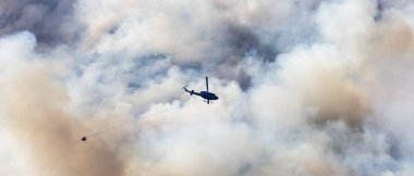 Sıcak bir yaz günü, Hope yakınlarındaki dağda, BC Orman Yangını ve Dumanı 'nın üzerinde uçan Wildfire Servis Helikopteri. British Columbia, Kanada. Doğal Felaket