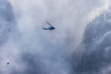 Sıcak bir yaz günü, Hope yakınlarındaki dağda, BC Orman Yangını ve Dumanı 'nın üzerinde uçan Wildfire Servis Helikopteri. British Columbia, Kanada. Doğal Felaket