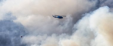 Sıcak bir yaz günü, Hope yakınlarındaki dağda, BC Orman Yangını ve Dumanı 'nın üzerinde uçan Wildfire Servis Helikopteri. British Columbia, Kanada. Doğal Felaket