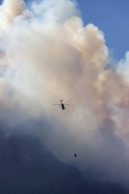Sıcak bir yaz günü, Hope yakınlarındaki dağda, BC Orman Yangını ve Dumanı 'nın üzerinde uçan Wildfire Servis Helikopteri. British Columbia, Kanada. Doğal Felaket