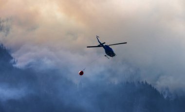 Sıcak bir yaz günü, Hope yakınlarındaki dağda, BC Orman Yangını ve Dumanı 'nın üzerinde uçan Wildfire Servis Helikopteri. British Columbia, Kanada. Doğal Felaket