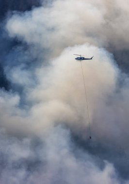 Sıcak bir yaz günü, Hope yakınlarındaki dağda, BC Orman Yangını ve Dumanı 'nın üzerinde uçan Wildfire Servis Helikopteri. British Columbia, Kanada. Doğal Felaket