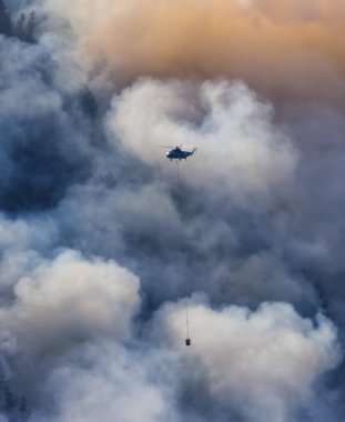 Sıcak bir yaz günü, Hope yakınlarındaki dağda, BC Orman Yangını ve Dumanı 'nın üzerinde uçan Wildfire Servis Helikopteri. British Columbia, Kanada. Doğal Felaket