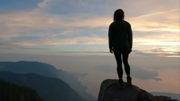 冒险的女性远足者在太平洋西海岸的加拿大山地景观的顶部 戏剧性的落日和烟雾弥漫的天空 加拿大温哥华附近的圣马可峰 慢动作电影 — 图库视频影像