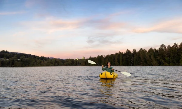 Adventurous Woman Kayaking on an Inflatable Kayak in the Pacific Ocean. Sunset Sky. Port Moody, Vancouver, British Columbia, Canada. Adventure Sport Travel