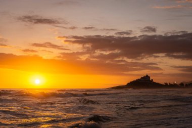 Itauna 'dan okyanusa güzel bir günbatımı manzarası ve tepedeki eski kilise Saquarema, Rio de Janeiro, Brezilya