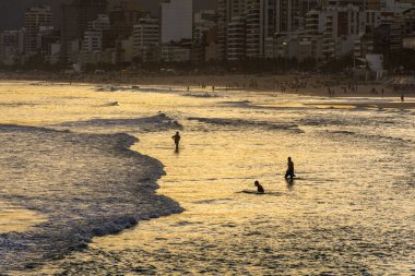 Ipanema 'da banyo yapan insanlar için güzel sahil gün batımı manzarası, Rio de Janeiro, Brezilya