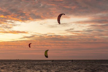Beautiful view to kitesurfers and golden sunset clouds in Atins Beach, Lenis Maranhenses, Maranho State, Brazil.