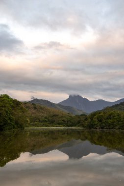 Brezilya 'nın Rio de Janeiro eyaletinde, REGUA' daki yeşil yağmur ormanı gölü ve dağlarda güneşin doğuşuna güzel bir manzara