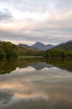 Brezilya 'nın Rio de Janeiro eyaletinde, REGUA' daki yeşil yağmur ormanı gölü ve dağlarda güneşin doğuşuna güzel bir manzara