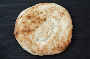 Siyah ahşap masada susam tohumlu buğday tortilla.