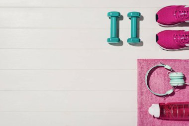 Beyaz ahşap döşeme arka planında fitness ya da vücut geliştirme kavramı. Evde antrenman için spor malzemeleri. Fotoğraf yukarıdan çekilmiş, üst görünümde bir sürü kopya alanı var