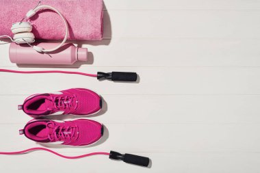 Beyaz ahşap döşeme arka planında fitness ya da vücut geliştirme kavramı. Evde antrenman için spor malzemeleri. Fotoğraf yukarıdan çekilmiş, üst görünümde bir sürü kopya alanı var