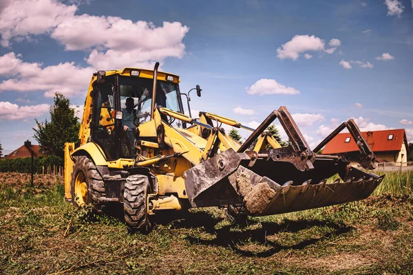 Excavator working at house construction site - digging foundations for modern house. Beginning of house building. Earth moving and foundation preparation.