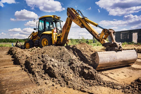 Ev inşaatında çalışan kazıcı modern ev için temel kazıyor. Ev inşaatı başlıyor. Toprak hareketi ve temel hazırlığı.