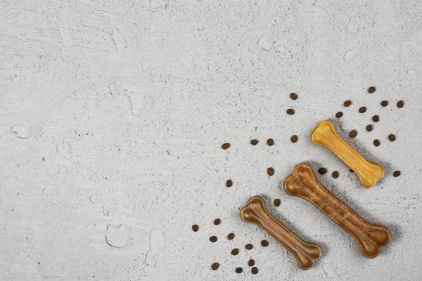 Dry dog pet food and accessories on gray concrete background top view. Pet feeding and care concept background with copy space. Photograph taken from above.