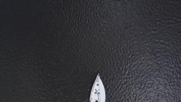 Sailing yacht on dark blue water going in and out of frame. Drone overhead shot. — Stock Video