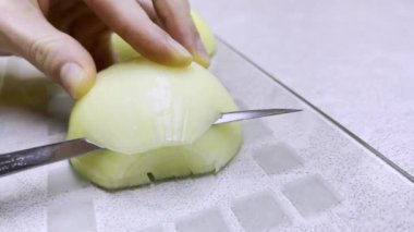 Kadın eli bıçaklı, cam kesme tahtasındaki soğanı dilimliyor. Kapat..