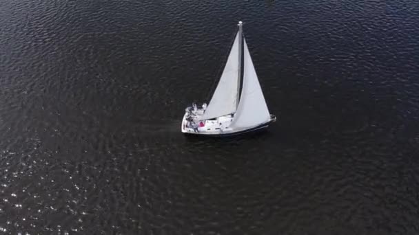 Vit segelbåt. Skjuta från en drönare yacht på mörkblått vatten, ovanifrån. — Stockvideo