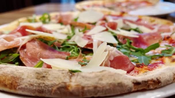 Cierra la pizza. Pizza de jamón con queso parmesano y hojas de rúcula. — Vídeos de Stock
