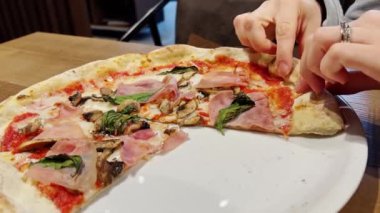 Female hands taking slices of pizza.