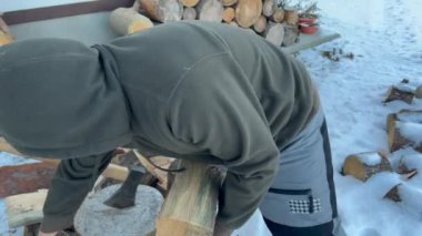 Man taking and holding pile of chopped fire wood prepared for winter. Logs of fire wood on background. lumberjack carrying firewood logs. Shot on axe at the end.