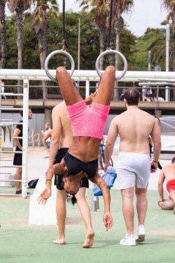 Barselona, İspanya - 24 Eylül 2021: Barceloneta plajında yüzüklerle egzersiz yapan genç siyahi kadın.