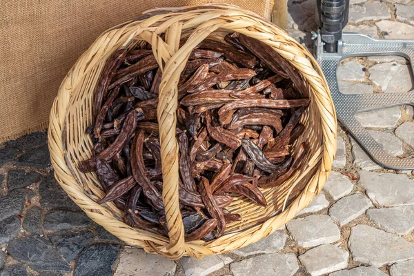 A basket with carob beans in a street market