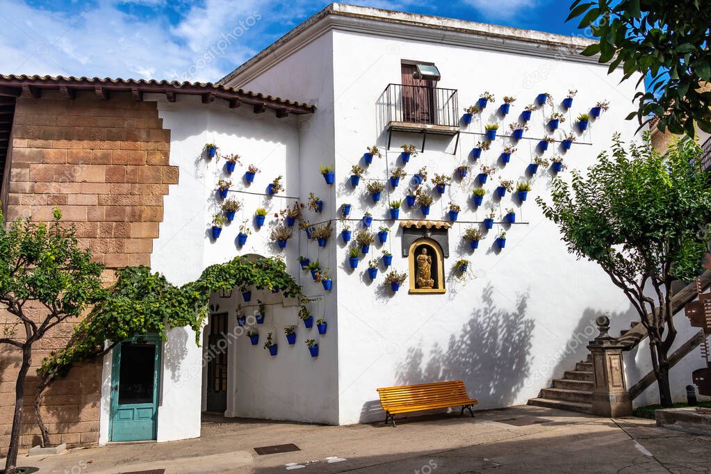 Andalusian neighborhood with blue flower pots hanging on the white walls of Arcos de la frontera, in Poble Espanyol, Spanish Village in Barcelona, Catalonia, Spain.