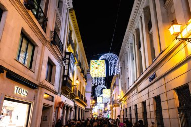 Seville, İspanya - Aralık 03.2021: Noel zamanı Seville Katedrali 'nde yürüyen kimliği belirsiz insanlar. Koronavirüs virüsü yüzünden koruyucu yüz maskesi takan insanlar.