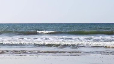 Punta Umbria sahilinde dalgalar boş plaja çarpıyor. Güneş ışığındaki plaj denizi manzarası