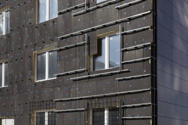 Bir evin termal korunması için izolasyon, ofis binası cephesi. Tuğla duvarın mineral yünüyle termal yalıtımı