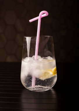 Buzlu su ve limon dilimleri koyu arkaplanda cam bir deney şişesinde. Soğuk içecek konsepti