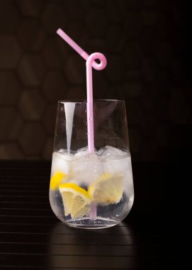Buzlu ve limonlu tonik. Koyu bir arka planda cam bir şişede. Soğuk içecek konsepti