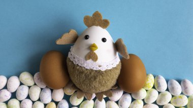 Mavi arka planda yumurtaları olan tavuk bebek..