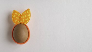 Egg with spots rabbit ears on white paper background. Copy space. Flat lay.