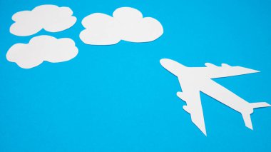 Paper plane in the clouds on a blue background. Concept of flight, travel. Copy space, flat lay, banner