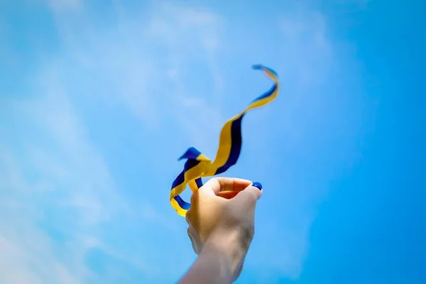 Hand håller blå gult band på himlen bakgrund. Ukrainas flagga frihet självständighet — Stockfoto