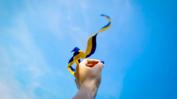 Mão segura fita amarela azul no fundo do céu. Bandeira da Ucrânia liberdade conceito de independência — Fotografia de Stock