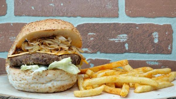 Karamelli soğan, marul, çedar peyniri, soğan, domates ve patates kızartmalı sulu ızgara çizburger.