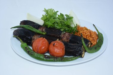 Patlıcan kebabı, bulgur pilavı, soğan, görüşme, kavrulmuş domates ve biberle servis edilir..