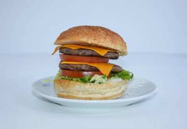 Duble çizburgerin yanına beyaz tabakta servis edilen çedar peyniri koyun. Beyazda izole edilmiş. Restoran broşürü ve menüsü için..