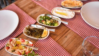 Akdeniz ve Ege soğuk aperatifleri kırmızı masa örtüsüyle ahşap bir masada servis edilir.