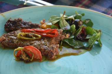 Sebzeli bifteği mavi tabakta yakın.