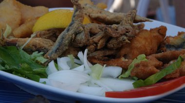 Restoranda sebze tabağında balık tabağı, kızarmış balık tabağı. Kızarmış ançüez balığı beyaz tabakta Whit salatası.