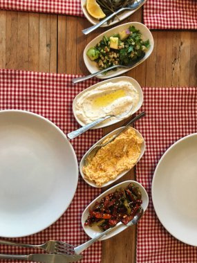 Akdeniz ve Ege soğuk aperatifleri kırmızı masa örtüsüyle ahşap bir masada servis edilir.