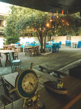 Renkli Ege tavernası, Gökceada, Imbros adasındaki restoran. Masalar, antika eşyalar, antika saat.