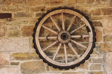 Eski bir taş duvarda eski bir araba tekerleği